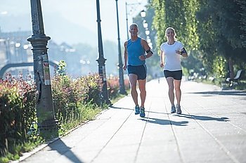 healthy mature couple jogging in the city  at early morning with sunrise in background