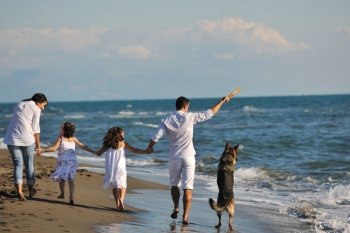 happy young family in white clothing have fun and play with beautiful dog at vacations on beautiful beach 