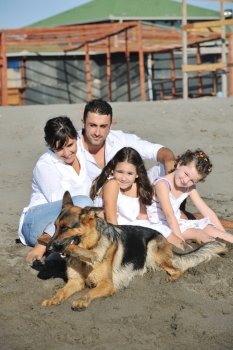 happy young family in white clothing have fun and play with beautiful dog at vacations on beautiful beach 