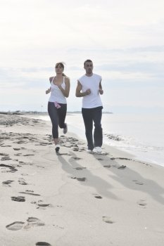 happy young couple running and jogging on beach at early morning
