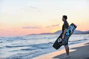 Portrait of a strong young  surf  man at beach on sunset in a contemplative mood with a surfboard