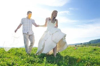 happy bride and groom walking and run on beautiful meadow outdoor at sunset