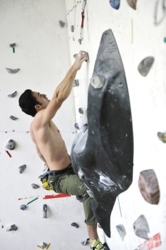 young and fit man exercise free mountain climbing on indoor practice wall