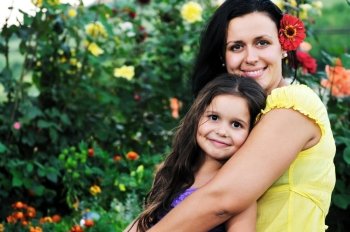 beautiful mom and daughter outdoor in garden  together with flower have fun and hug 