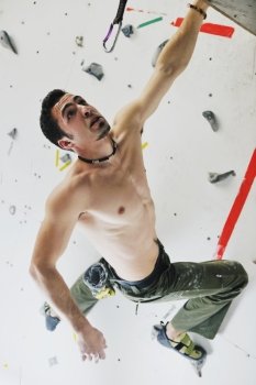 young and fit man exercise free mountain climbing on indoor practice wall