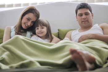 happy young family at home relaxing in bed 