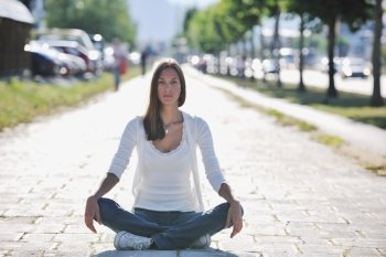 beautiful young woman meditating and exercise yoga in lotus position at street at beautiful sunny day with blured background