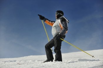 young man pointing direction on winter season during recration ski on mountain with show