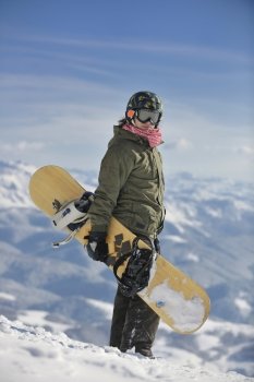snowboarder relaxing and posing at sunny day on winter season with blue sky in background