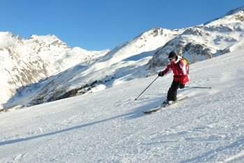 skier skiing downhill on fresh powder snow  with sun and mountains in background