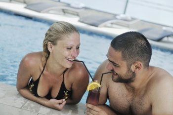 happy young couple in love have fun  relax and  drink coctail at indoor wellness swimming pool