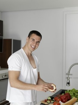 Handsome man cooking at home preparing salad in kitchen.