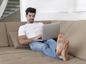 Man Relaxing On Sofa With Laptop In New Home