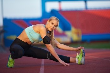 young runner sporty woman relaxing and stretching on athletic race track