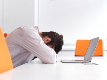Frustrated young business man have stress problems. Sitting alone at office meeting room  and working on laptop compute.