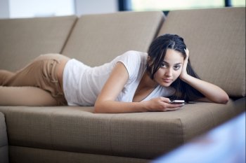 happy young woman using cellphone at home and relaxing