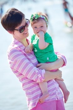 happy mom and baby on beach  have fun while learning to walk and  make first steps