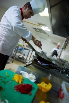 chef in hotel kitchen prepare vegetable  food with fire