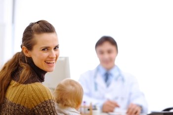 Happy mother with baby at pediatric doctor cabinet
