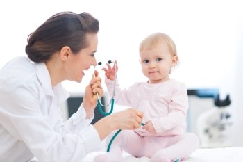 Pediatrician doctor playing with baby on examination