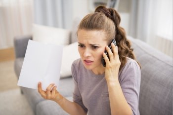 Stressed young woman holding letter and talking cell phone