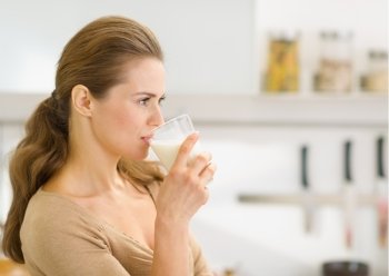 Young woman drinking milk in modern kitchen