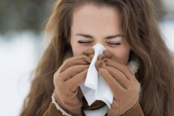 Young woman blowing nose in winter outdoors