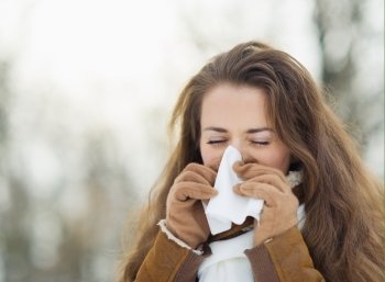 Woman blowing nose in winter outdoors
