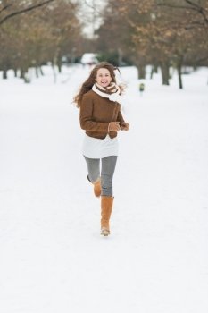 Happy young woman running in winter park
