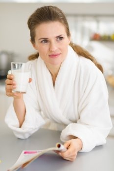 Young woman in bathrobe with milk and magazine