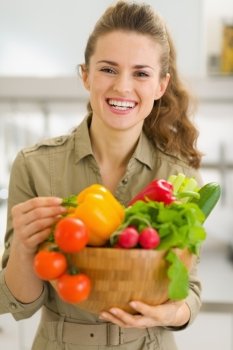 Portrait of smiling young woman with plate of fresh vegetables