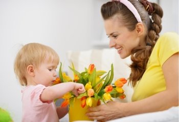 Happy mother and baby making decoration with bouquet of tulips in bucket