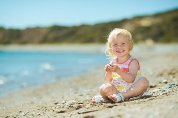 Happy baby girl playing on beach
