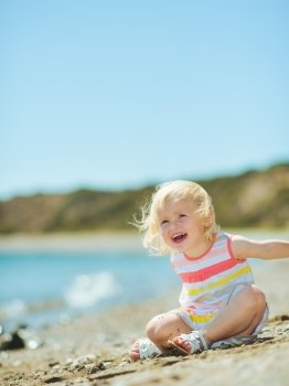 Happy baby girl playing with sand on beach