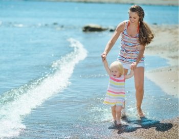 Mother and baby walking on beach