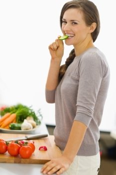 Happy young housewife tasting vegetables while preparing salad