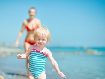 Mother and baby girl playing on sea shore