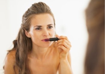 Woman choosing lipstick in bathroom