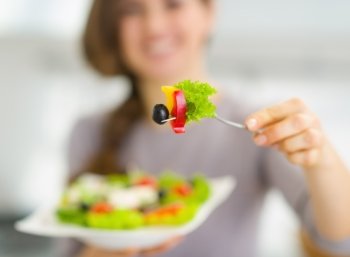 Closeup on fork with salad in hand of young woman