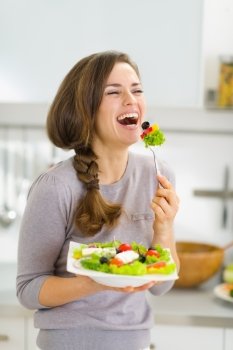 Happy young woman eating fresh salad