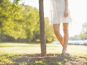 Closeup on young woman legs standing near seedling tree