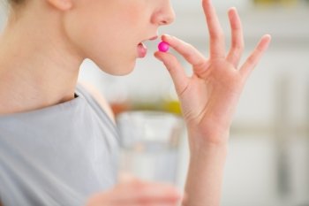 Closeup on young housewife eating pill