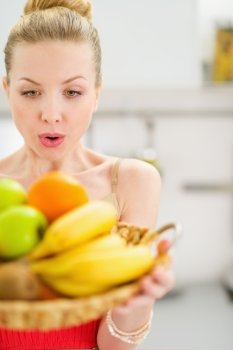 Surprised teenage girl holding plate of fruits