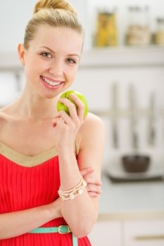 Happy teenage girl with apple in kitchen