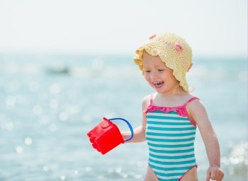 Smiling baby playing with pail on seashore