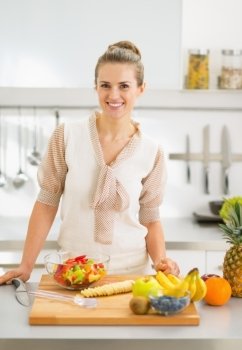 Happy young housewife cutting fruits in kitchen
