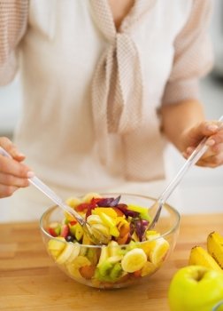Closeup on young housewife mixing fruits salad