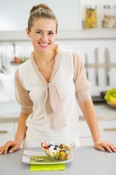 Smiling young housewife with fresh fruits salad