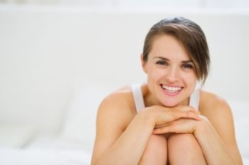 Portrait of happy woman sitting on bed