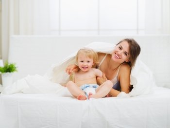 Portrait of smiling mother and baby in bedroom